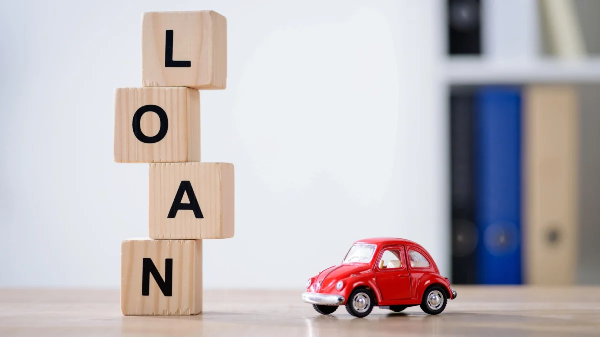wooden cubes with loan lettering and red toy car on wooden tabletop surface