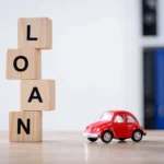 wooden cubes with loan lettering and red toy car on wooden tabletop surface