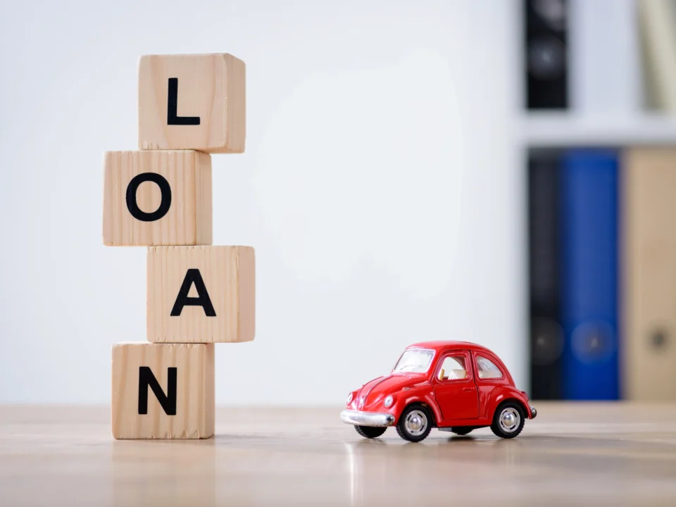 wooden cubes with loan lettering and red toy car on wooden tabletop surface