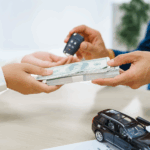 Hands counting money beside a miniature car
