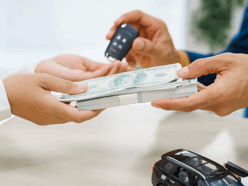 Hands counting money beside a miniature car