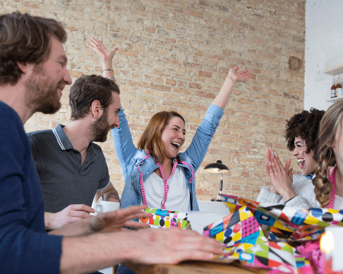 Group of people celebrating at a restaurant table with confetti